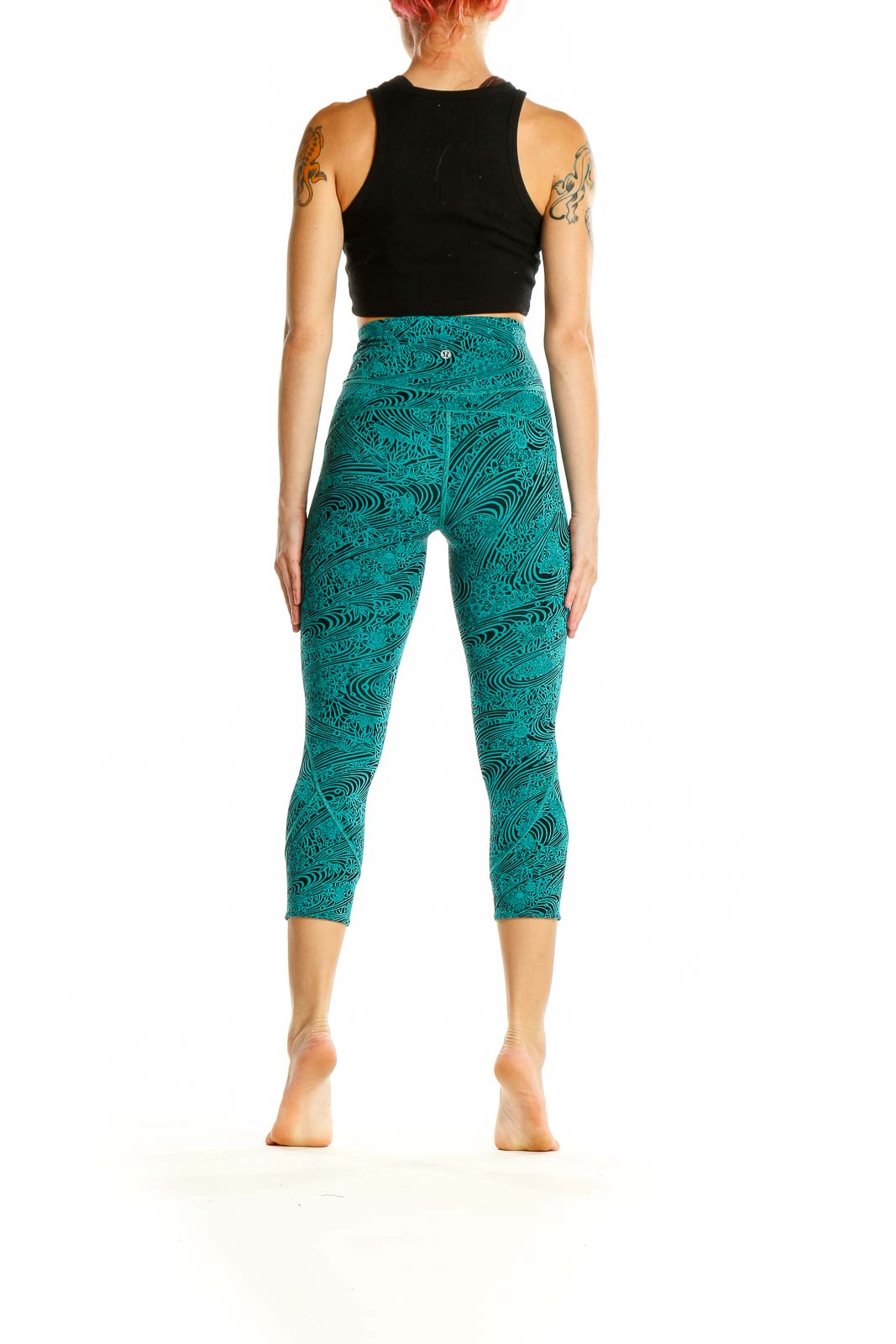 Side view of woman wearing teal Lululemon capri leggings and black crop top