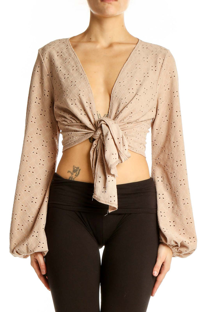 Front view of beige eyelet tie-front crop top with plunging neckline