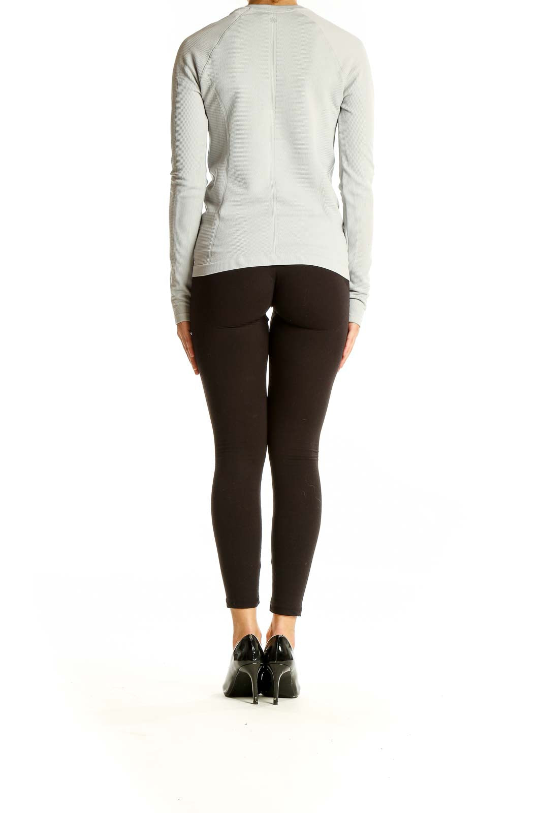 Side view of woman wearing Athleta light gray ribbed long sleeve athletic top with black leggings