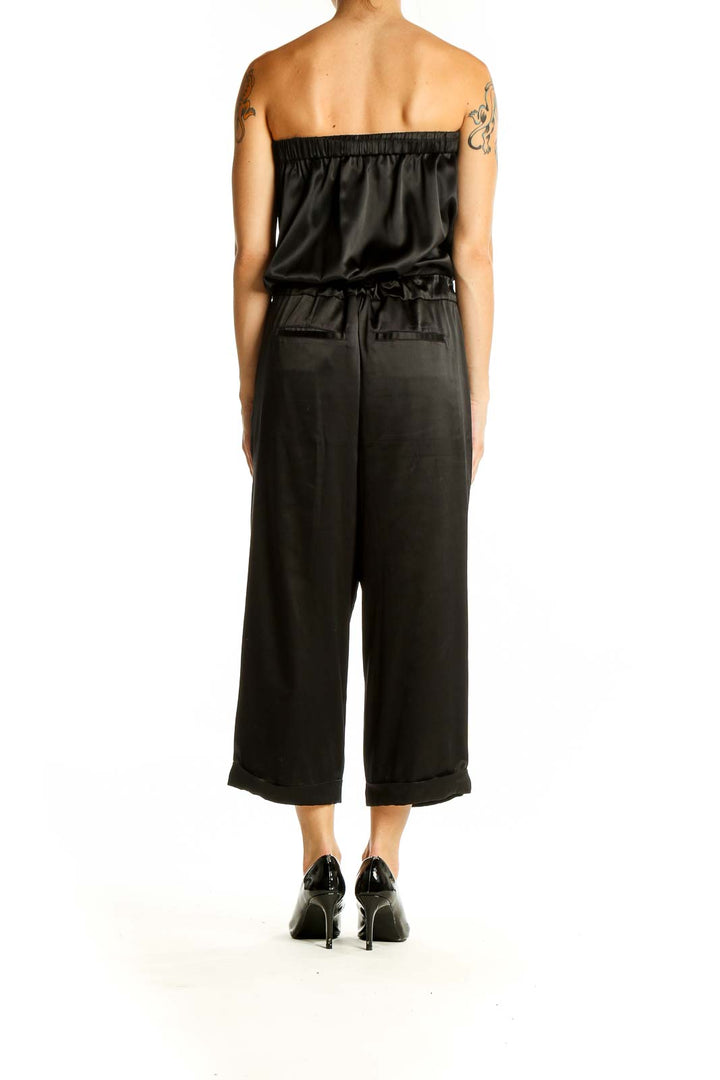 Side view of black strapless satin jumpsuit showing wide-leg design