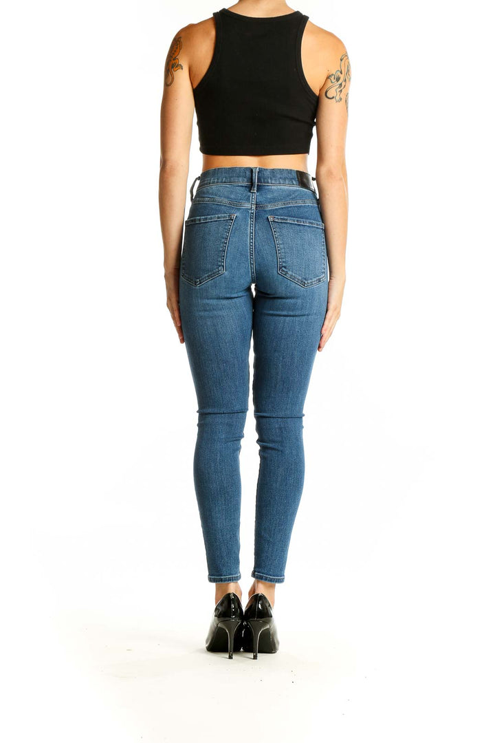 Side view of woman wearing Express blue high-waisted skinny jeans with black crop top