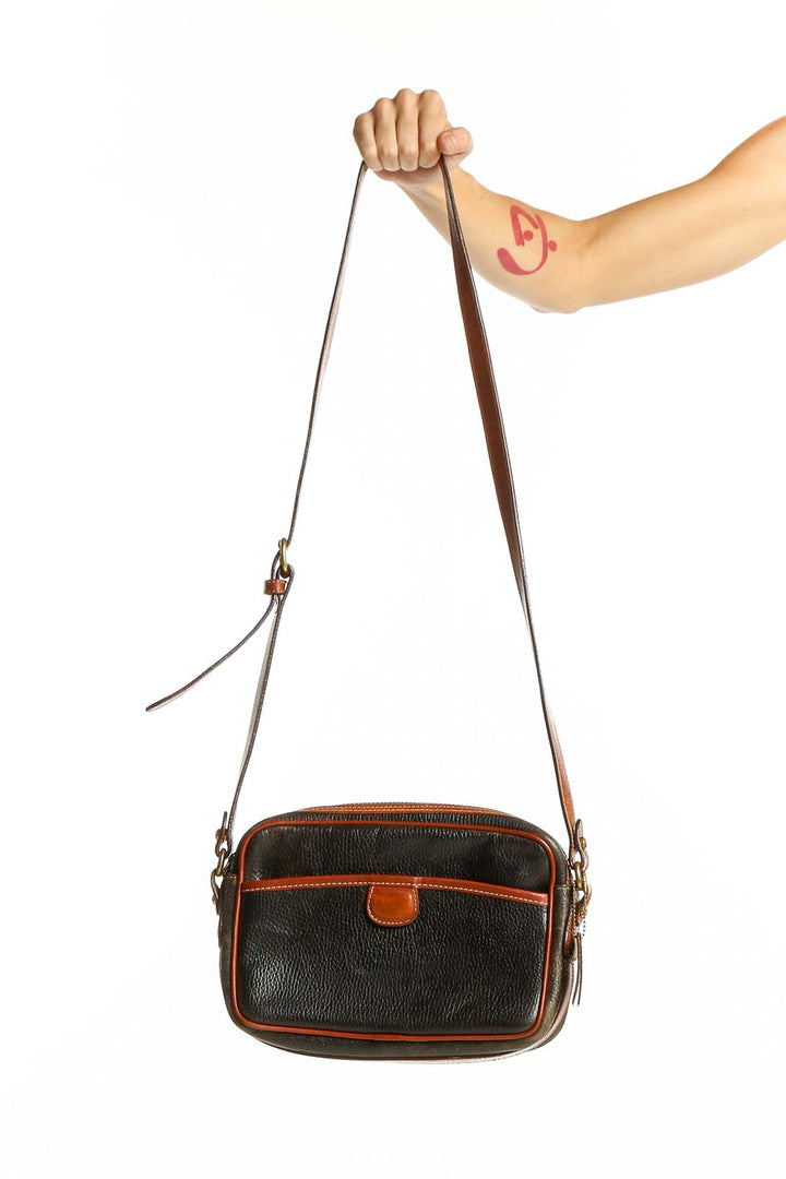 Front view of black leather Coach crossbody bag with brown trim