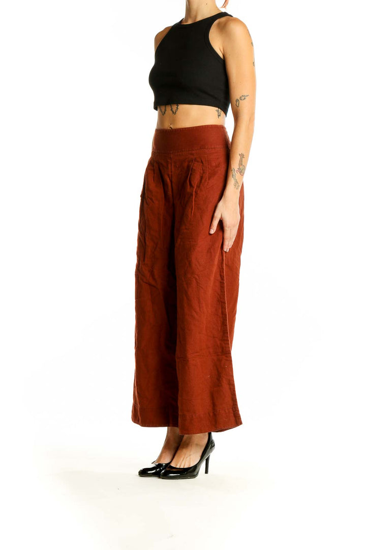 Front view of Anthropologie rust-colored wide-leg pants with side buttons