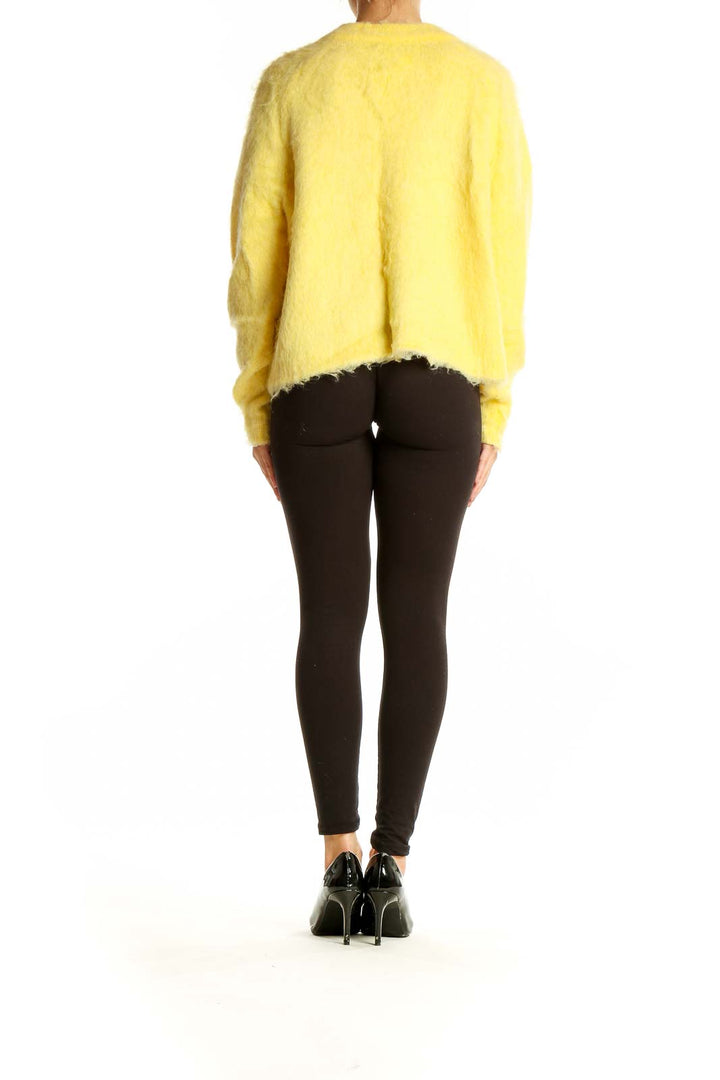 Side view of Madewell yellow fuzzy v-neck sweater on model with black pants