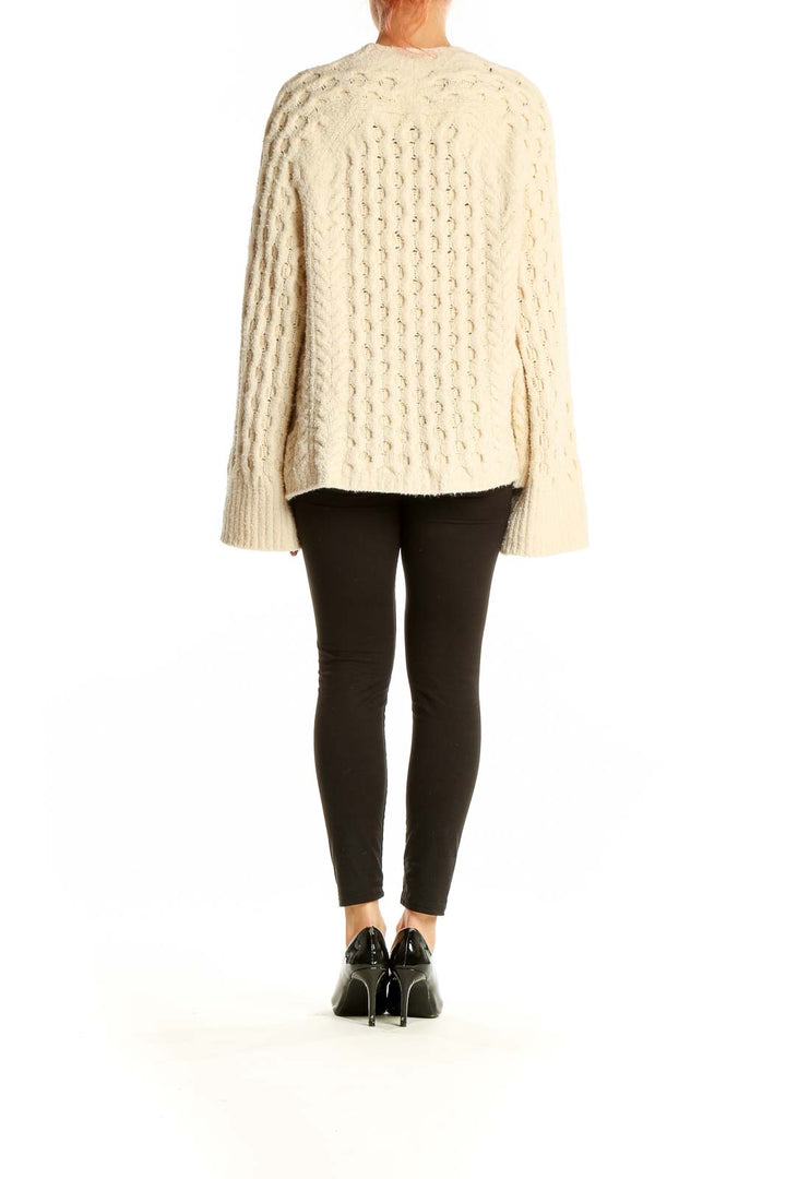 Side view of model wearing J.Crew cream cable knit sweater with black pants