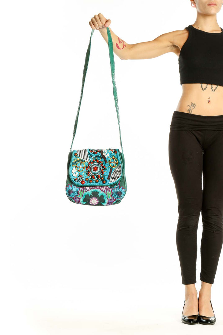 Front view of Desigual turquoise crossbody bag with colorful floral embroidery