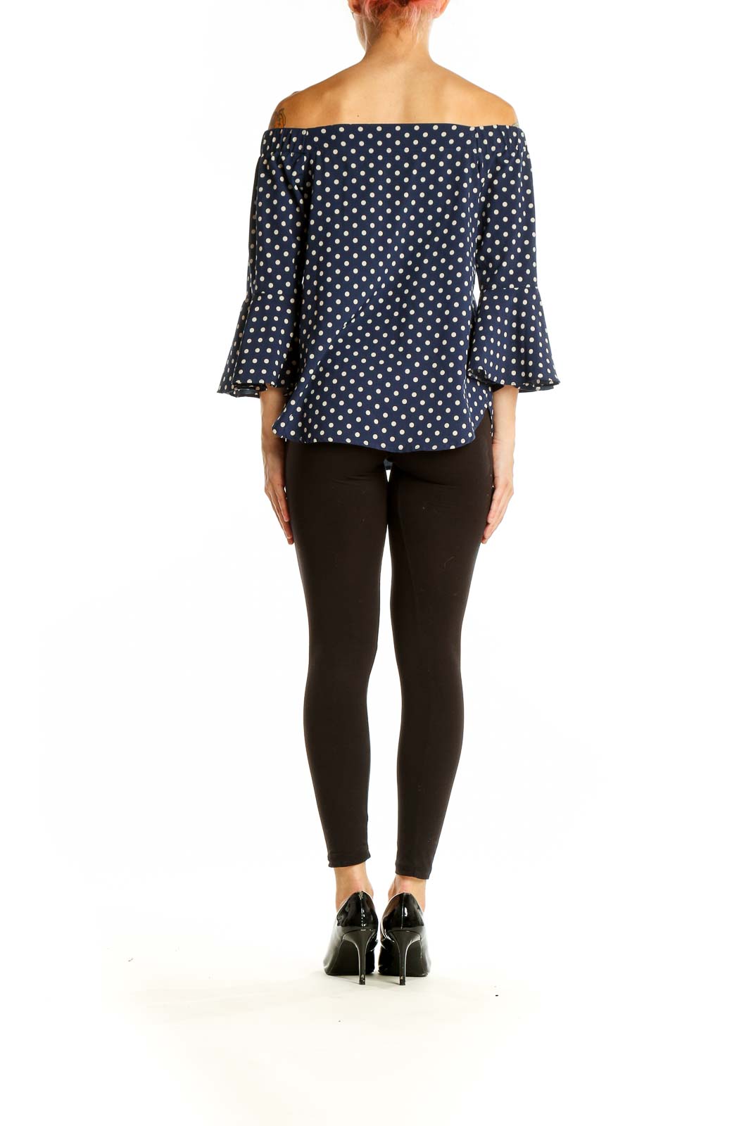 Side view of model wearing Camilla Tree navy polka dot off-shoulder top with black pants