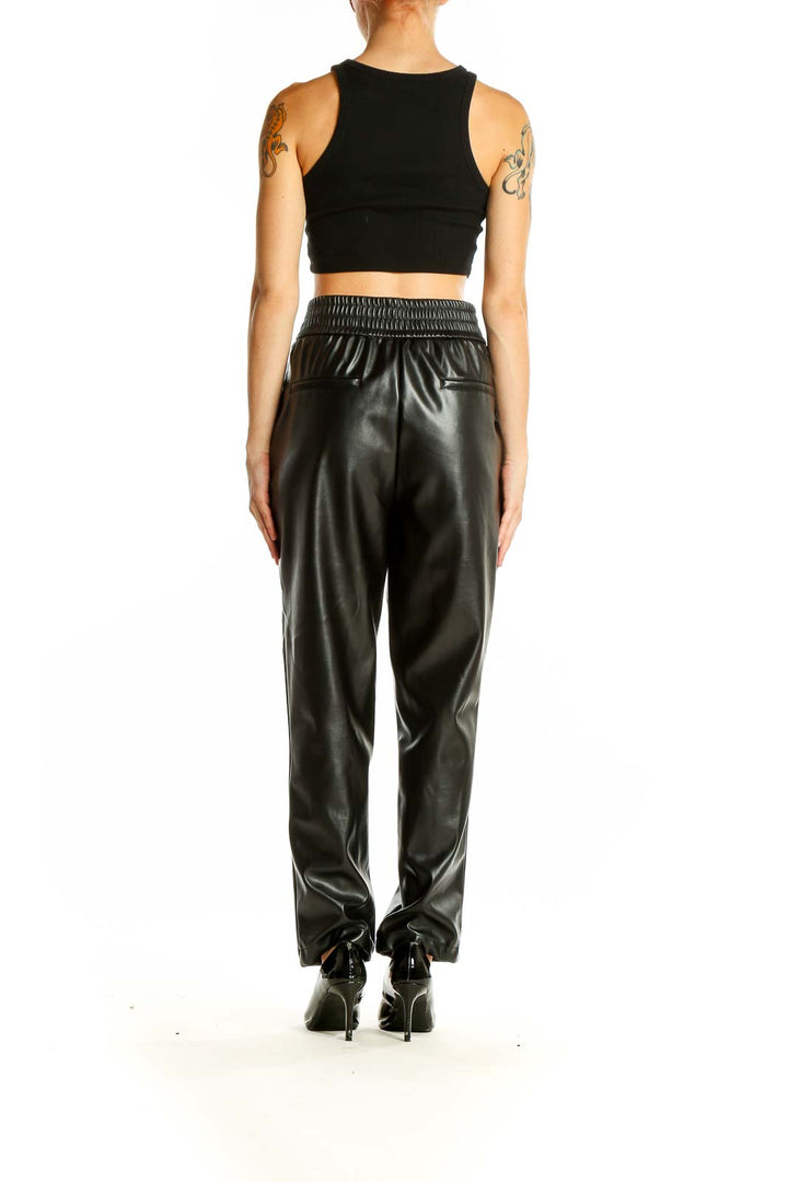 Side view of model wearing Maison D' Amelie Paris black faux leather wide-leg trousers with black crop top