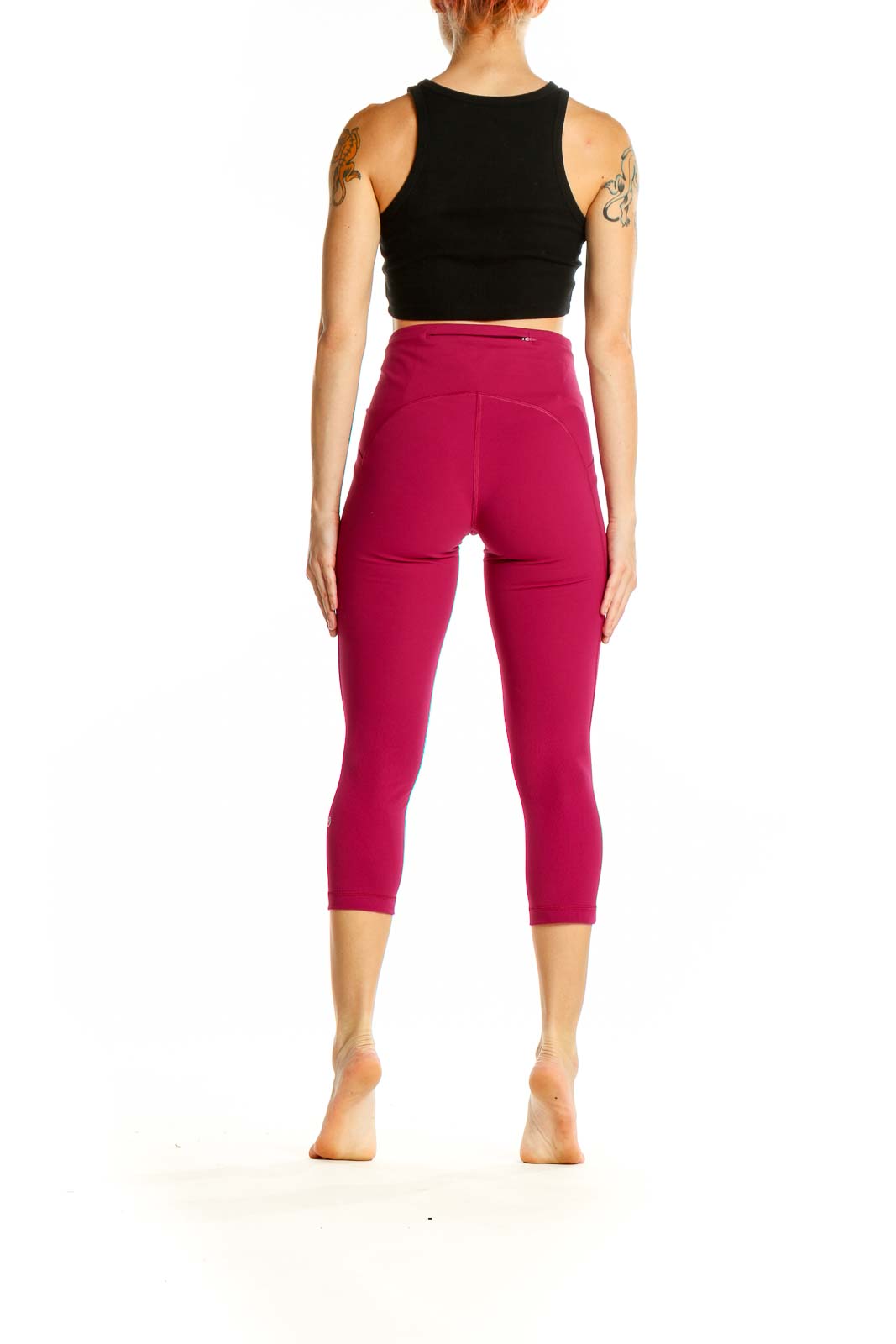 Side view of woman wearing burgundy Lululemon capri leggings with black crop top