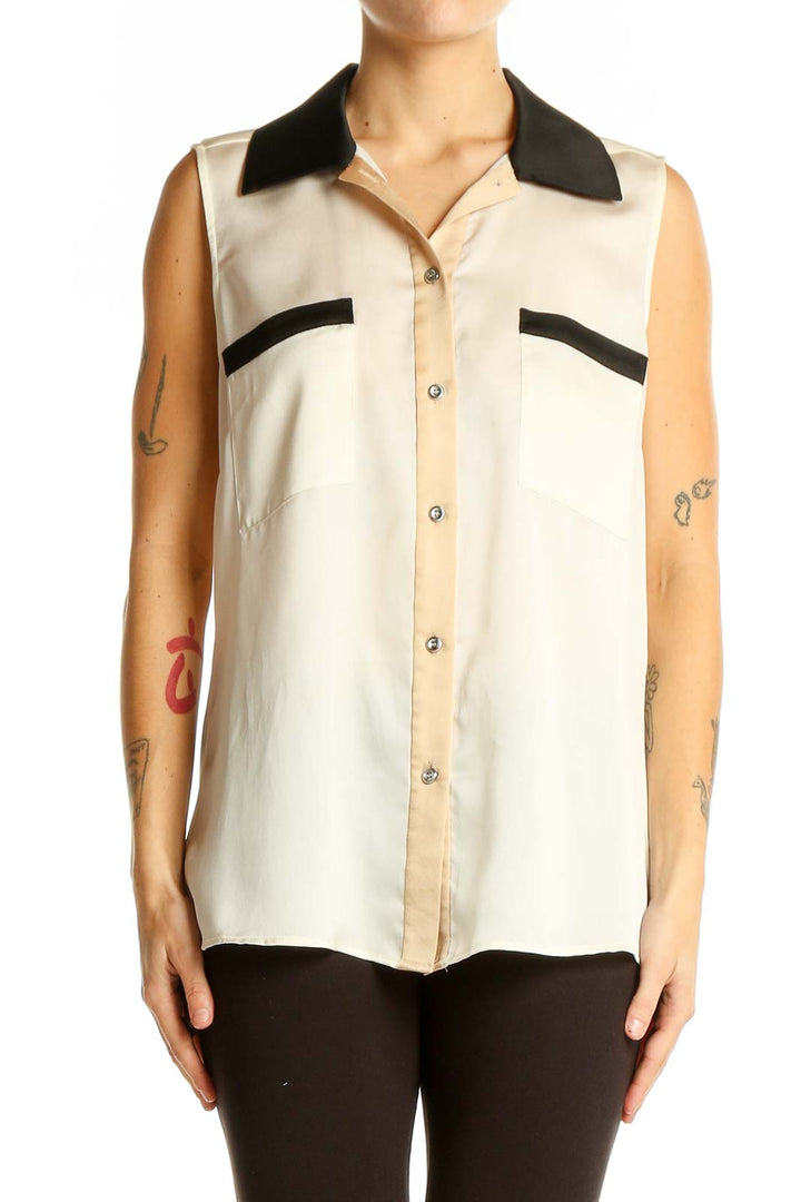 Front view of cream sleeveless blouse with black collar and pocket details