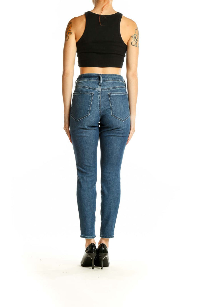 Side view of Athleta blue slim fit ankle-length jeans on model with black crop top