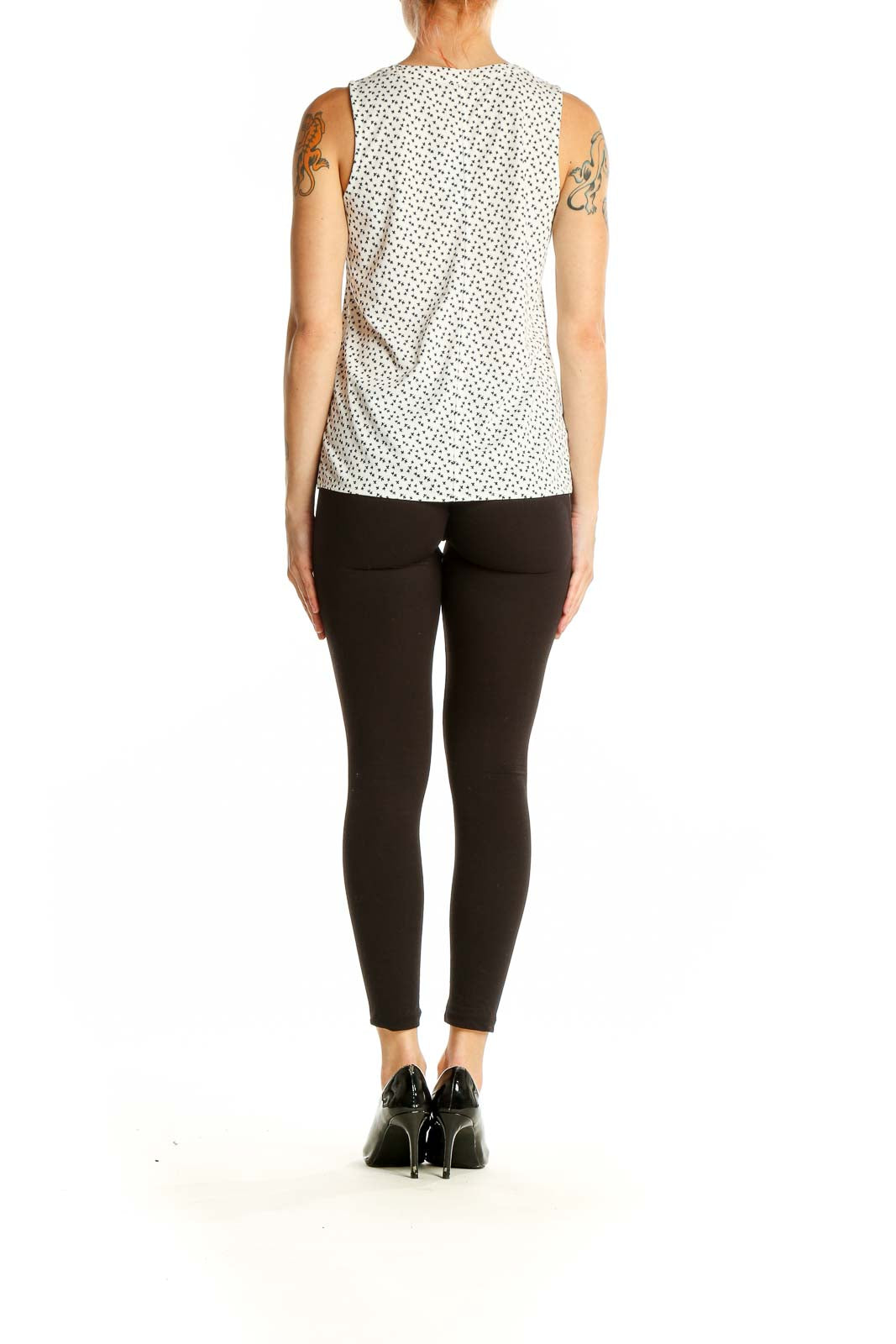 Side view of model wearing Ann Taylor white polka dot sleeveless blouse with black pants