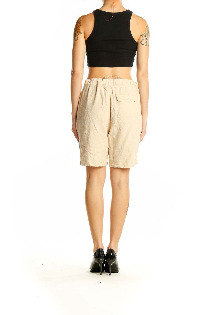 Side view of model wearing beige linen-blend shorts from onia with black top