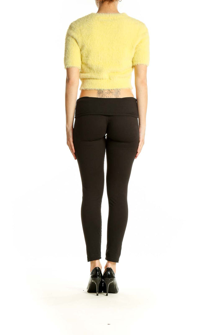 Side view of MAJORELLE yellow fuzzy cropped knit top with black pants