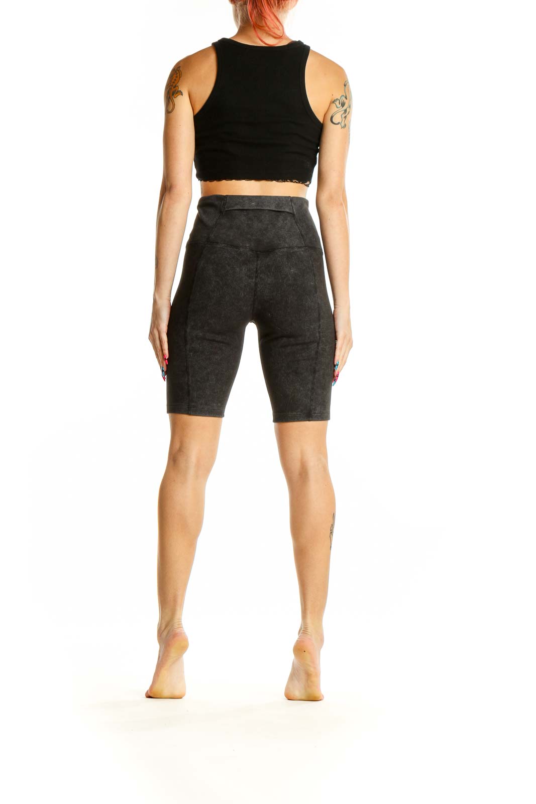 Side view of woman wearing Zella charcoal ribbed high-waist biker shorts with black crop top