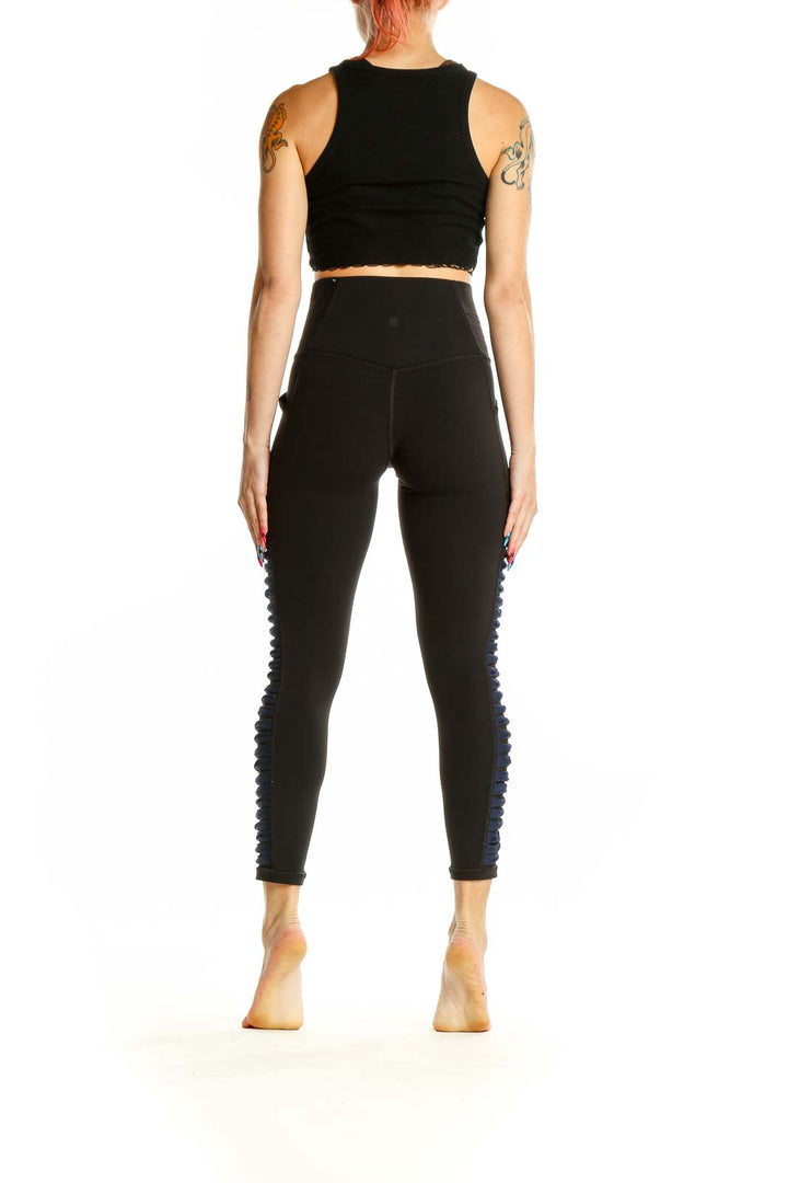 Side view of black Athleta high-waisted leggings showing blue side detailing