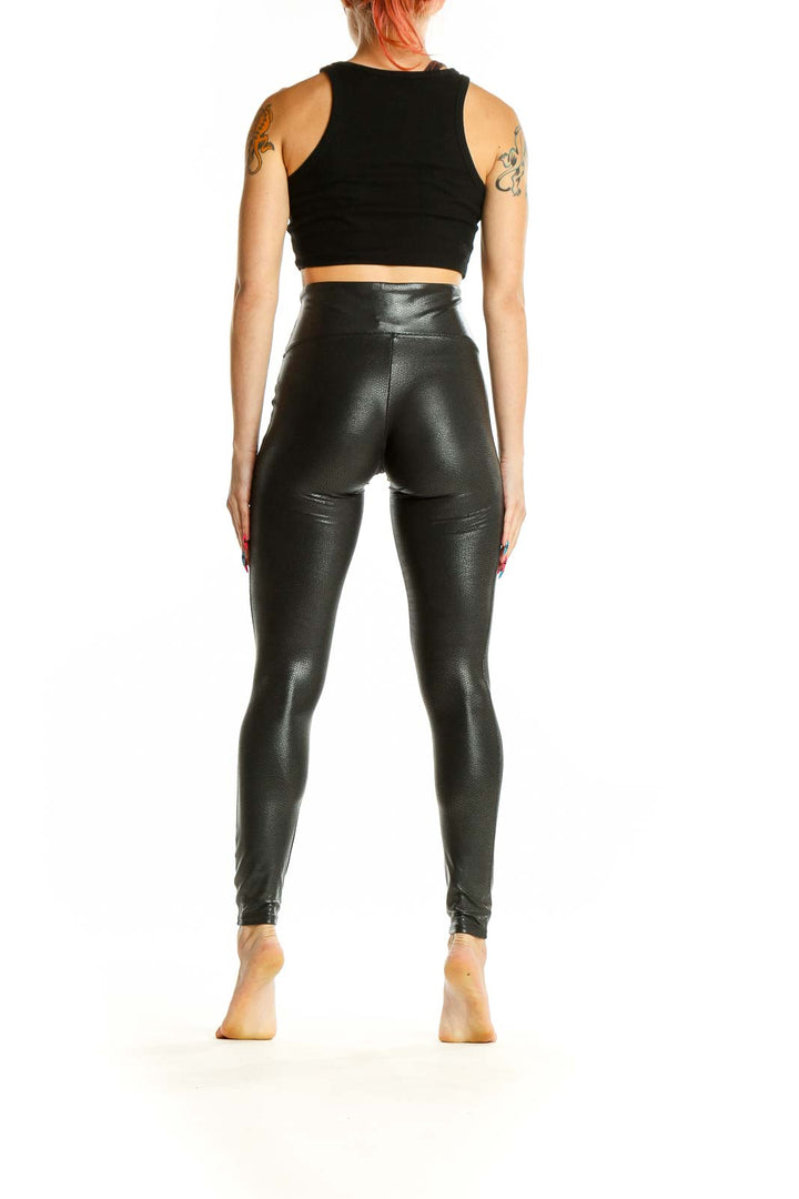 Side view of Spanx black faux leather high-waisted leggings on model with black crop top