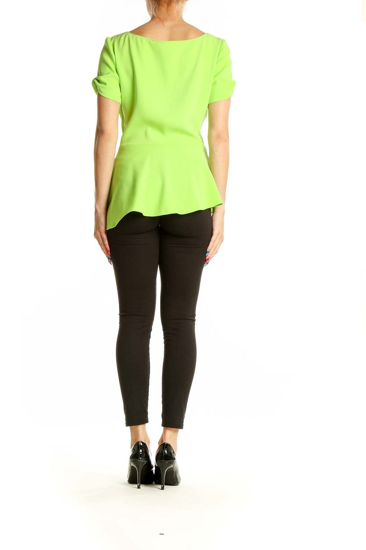 Side view of T Tahari lime green peplum short sleeve top on model