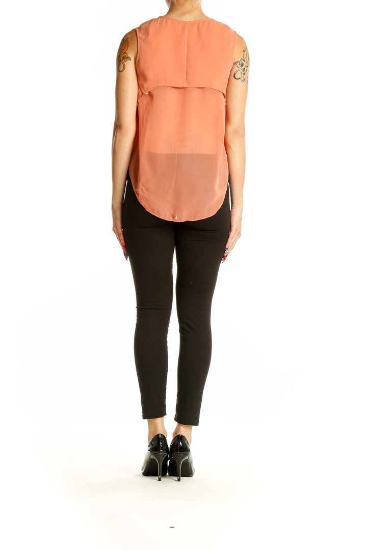 Back view of Rag & Bone peach sleeveless blouse on model with black pants