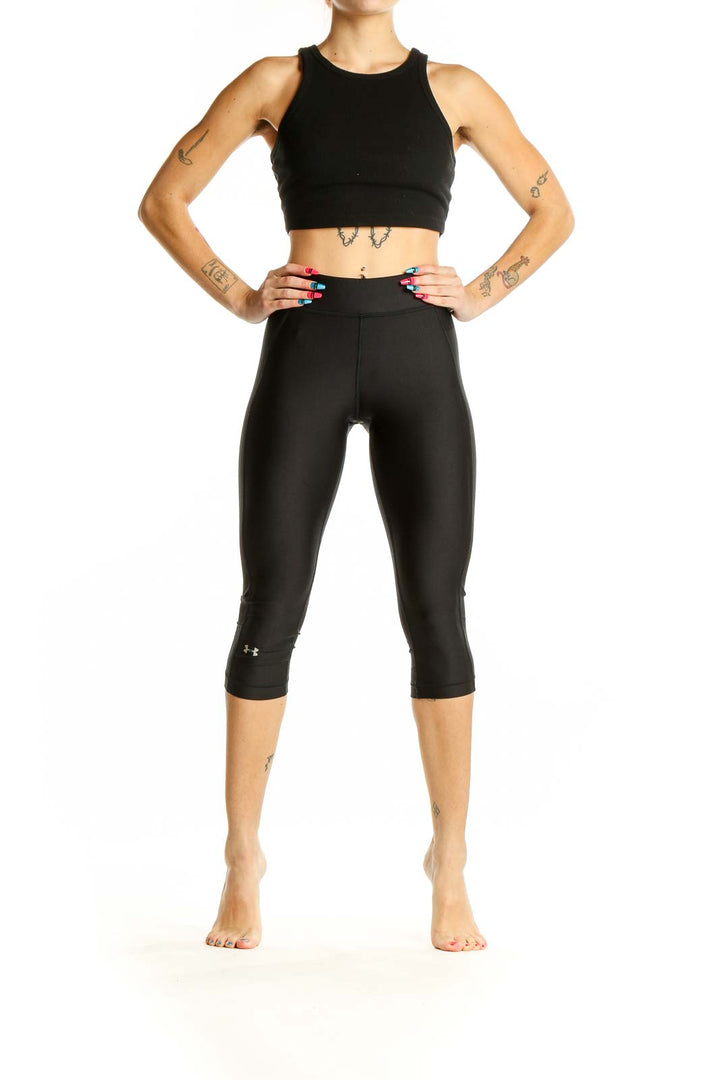 Front view of black Under Armour capri compression leggings on model