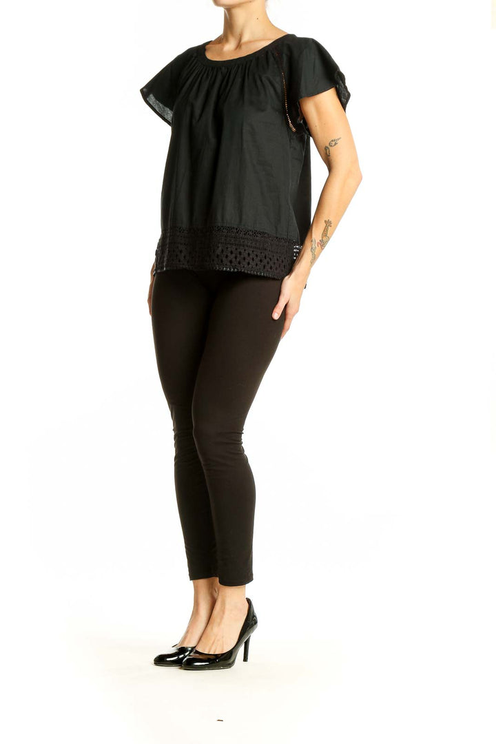 Front view of black flowy top with eyelet trim and flutter sleeves