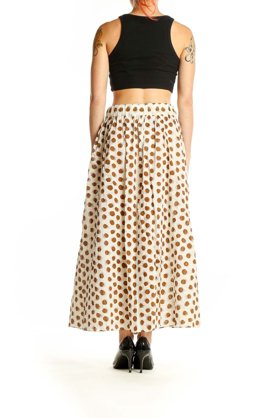 Side view of model wearing Mango white and brown polka dot cotton skirt with black top