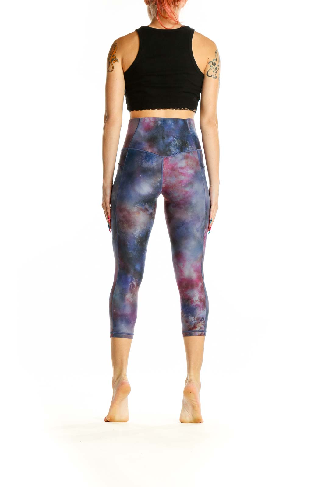 Side view of woman wearing Athleta cosmic tie-dye capri leggings with black crop top