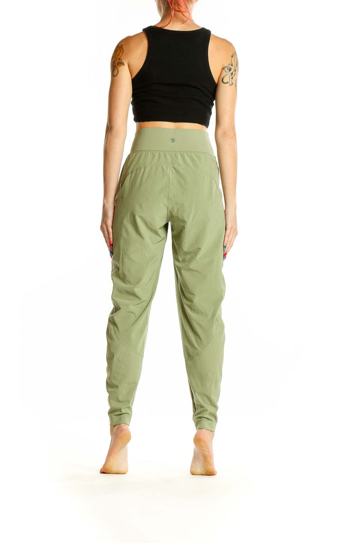 Side view of woman wearing Athleta sage green high-waisted activewear pants with black crop top