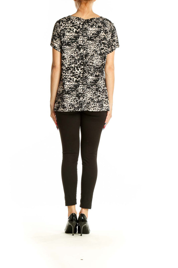 Side view of Alfani black and white speckled V-neck top on model