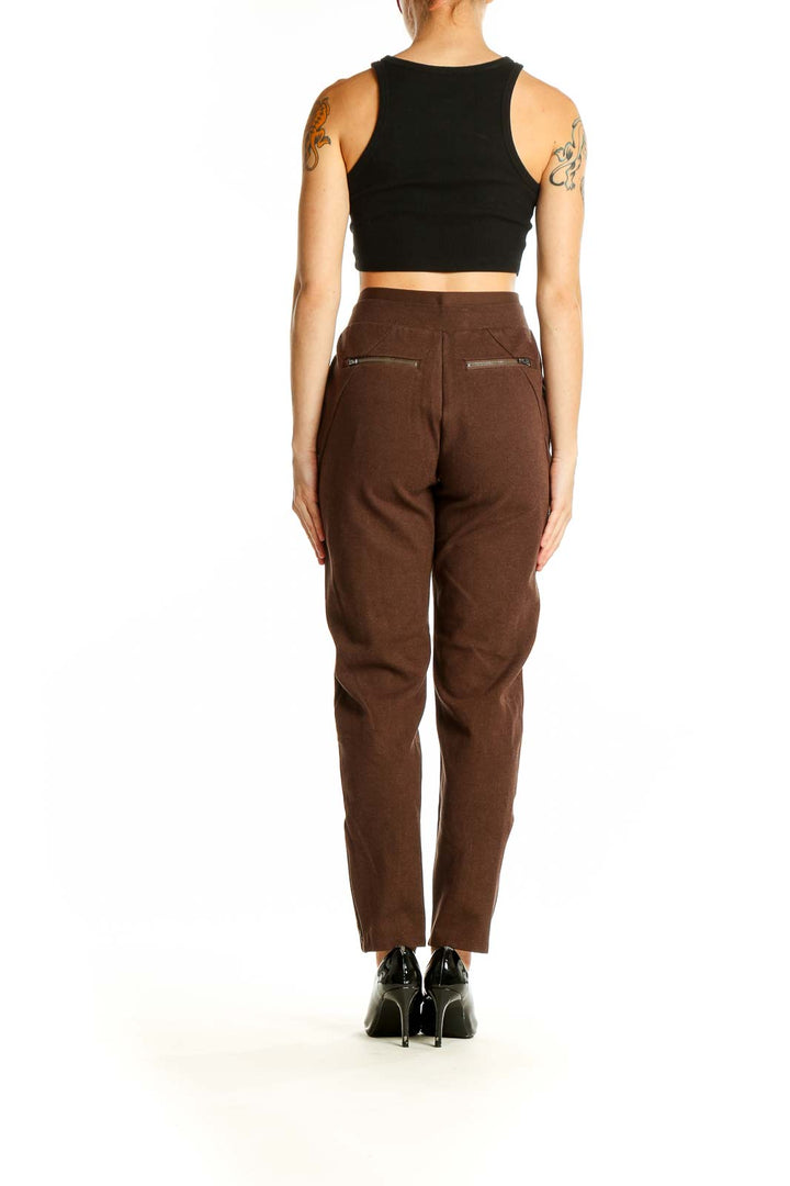 Side view of woman wearing Athleta brown high-waisted pleated trousers with black top