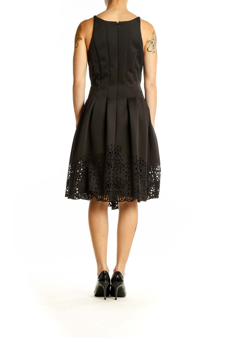 Side view of Vince Camuto black fit and flare dress showing laser-cut hem detail