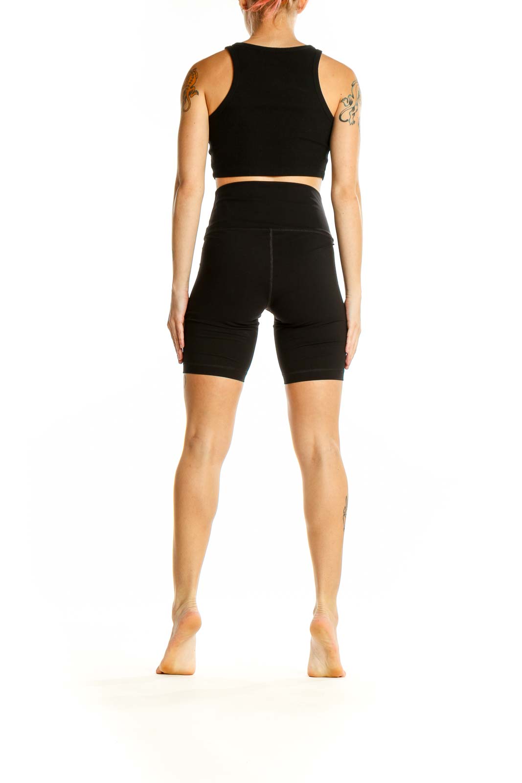 Side view of woman wearing black Everlane high-waisted biker shorts and crop top