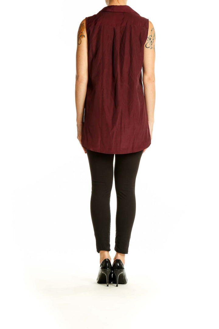 Side view of model wearing J.Crew burgundy sleeveless button-down blouse with black pants