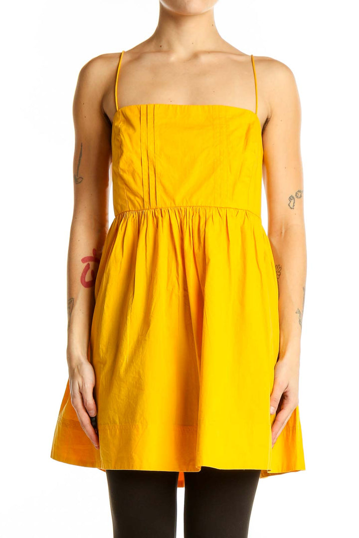 Front view of yellow cotton sundress with spaghetti straps and pleated bodice