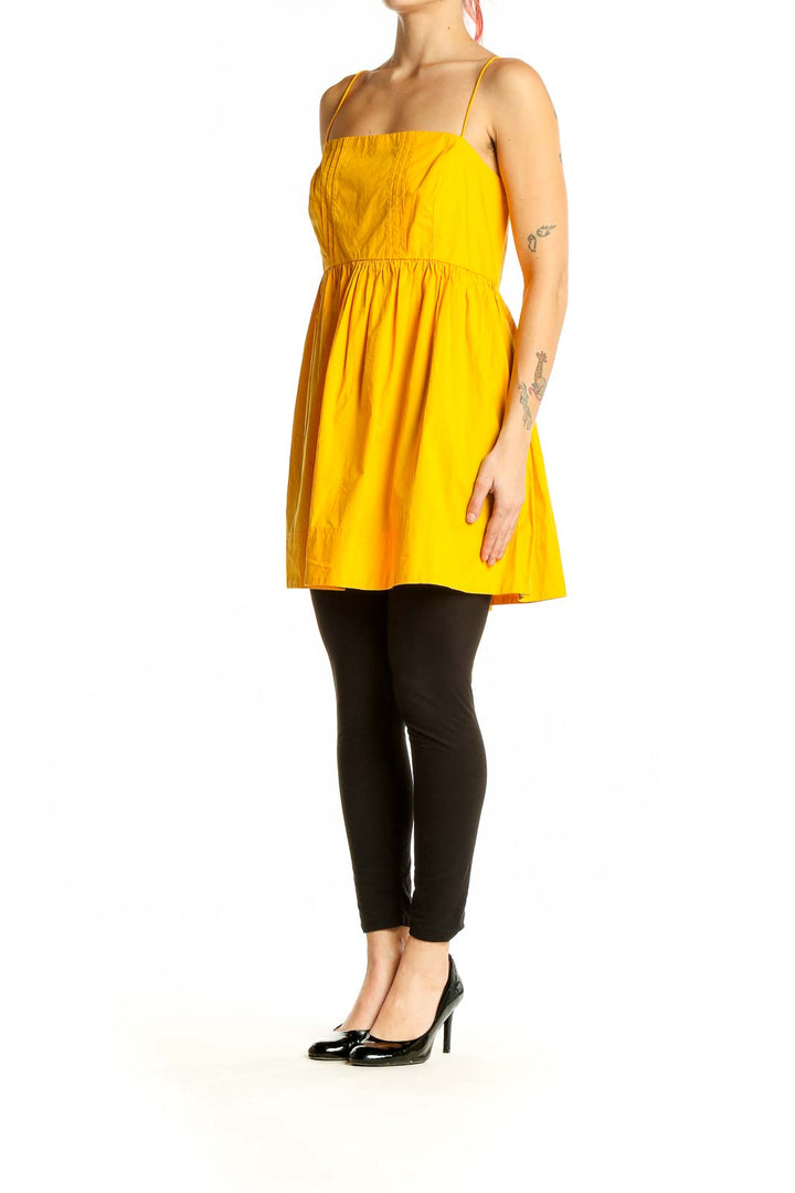 Front view of yellow cotton sundress with spaghetti straps and pleated bodice