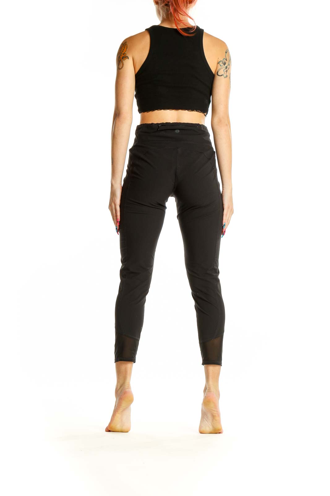 Side view of woman wearing black Athleta cropped activewear leggings with mesh panels