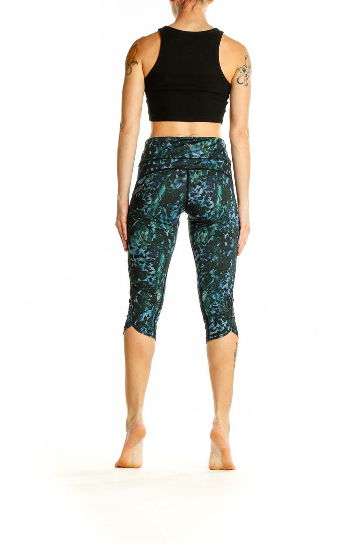 Side view of woman wearing Lululemon green patterned capri leggings with black top