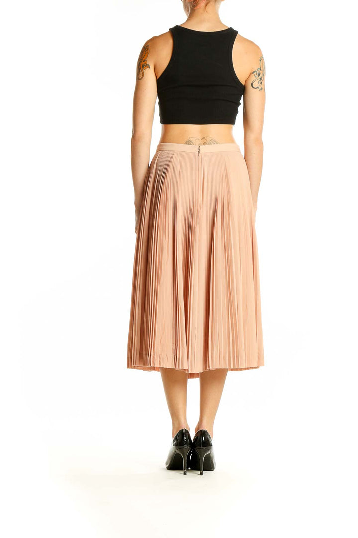 Side view of model wearing J.Crew peach pleated midi skirt with black top