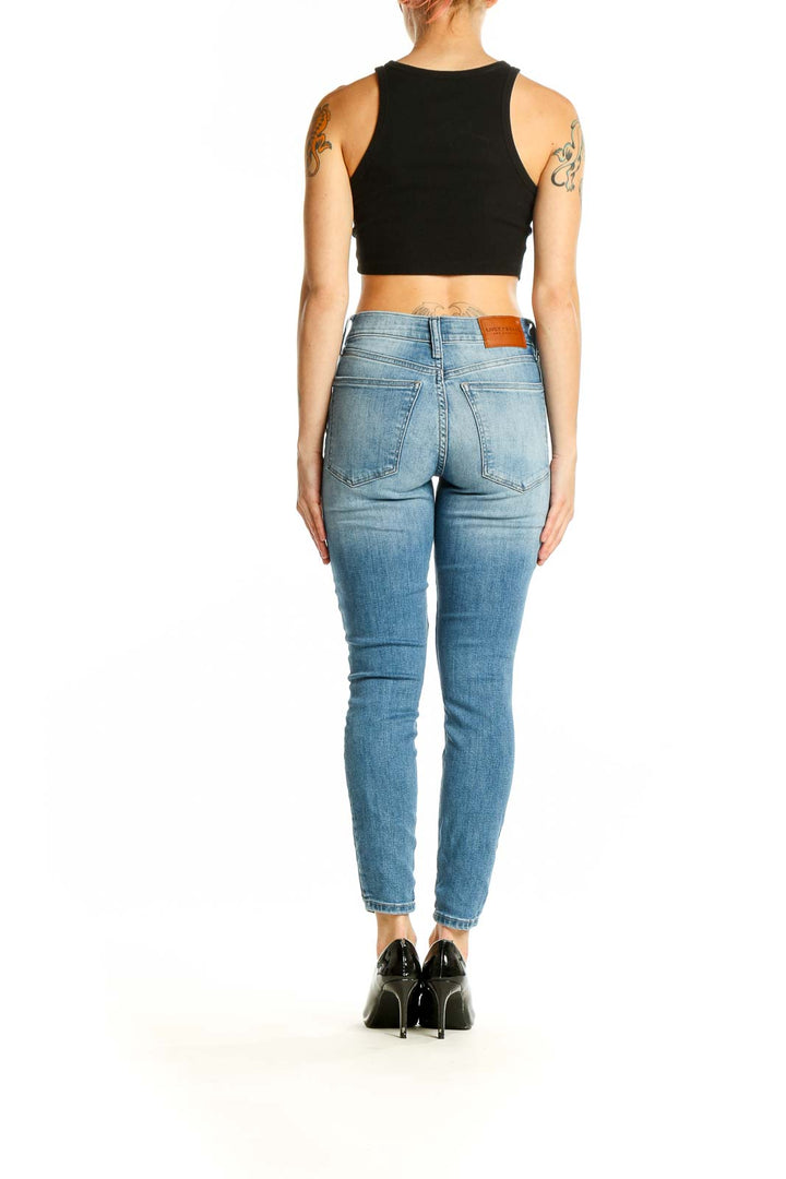 Back view of Lucky Brand light blue skinny ankle jeans on model with black crop top