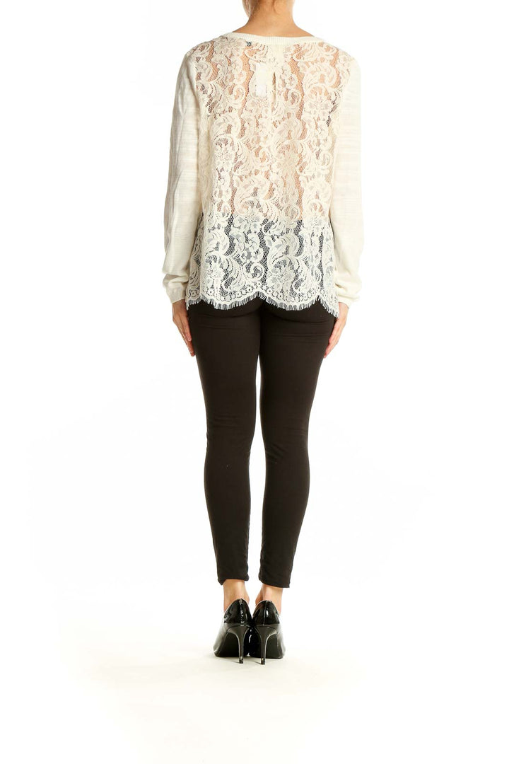 Side view of model wearing Cabi cream lightweight knit sweater with black pants