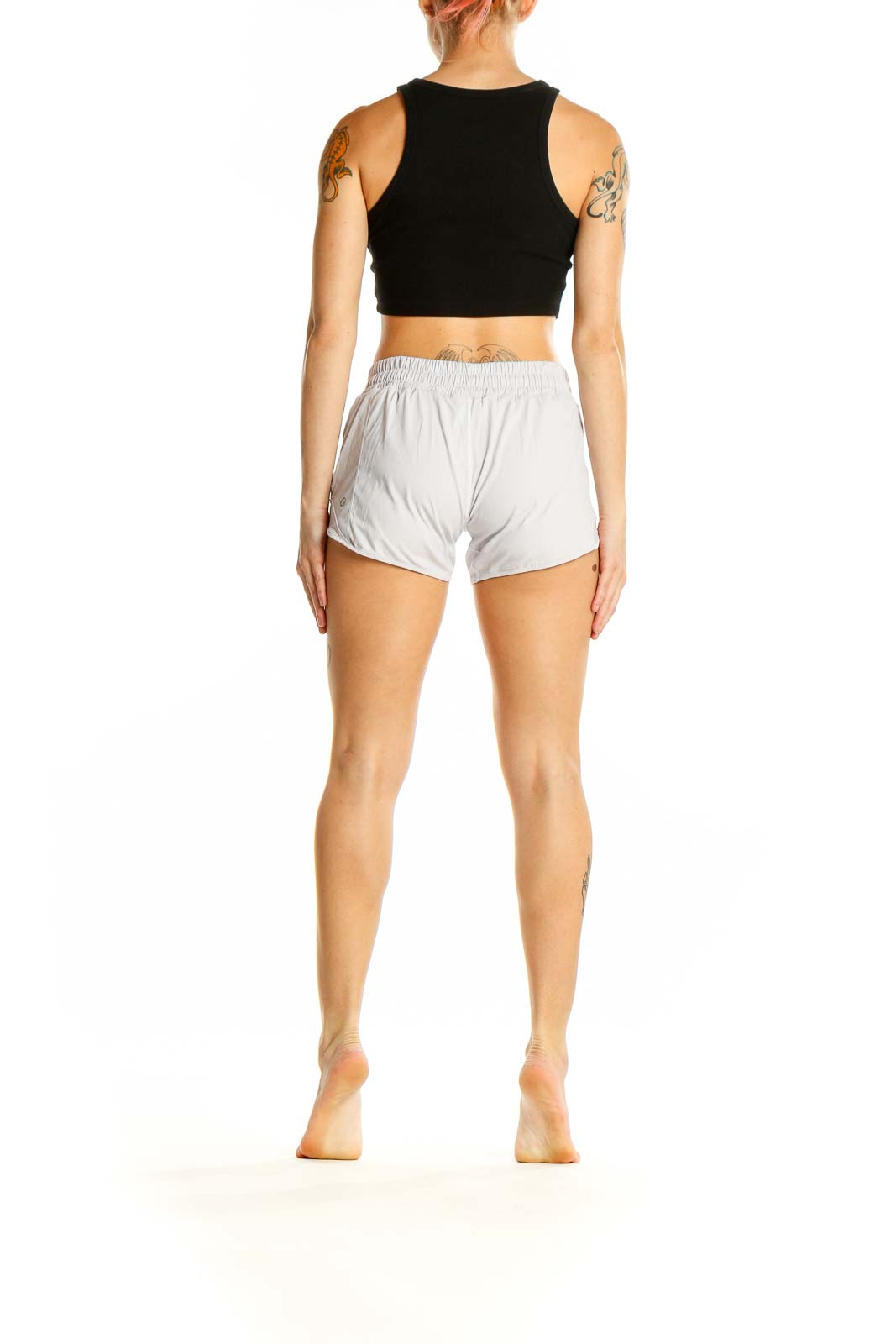 Side view of woman wearing white Lululemon athletic shorts and black crop top