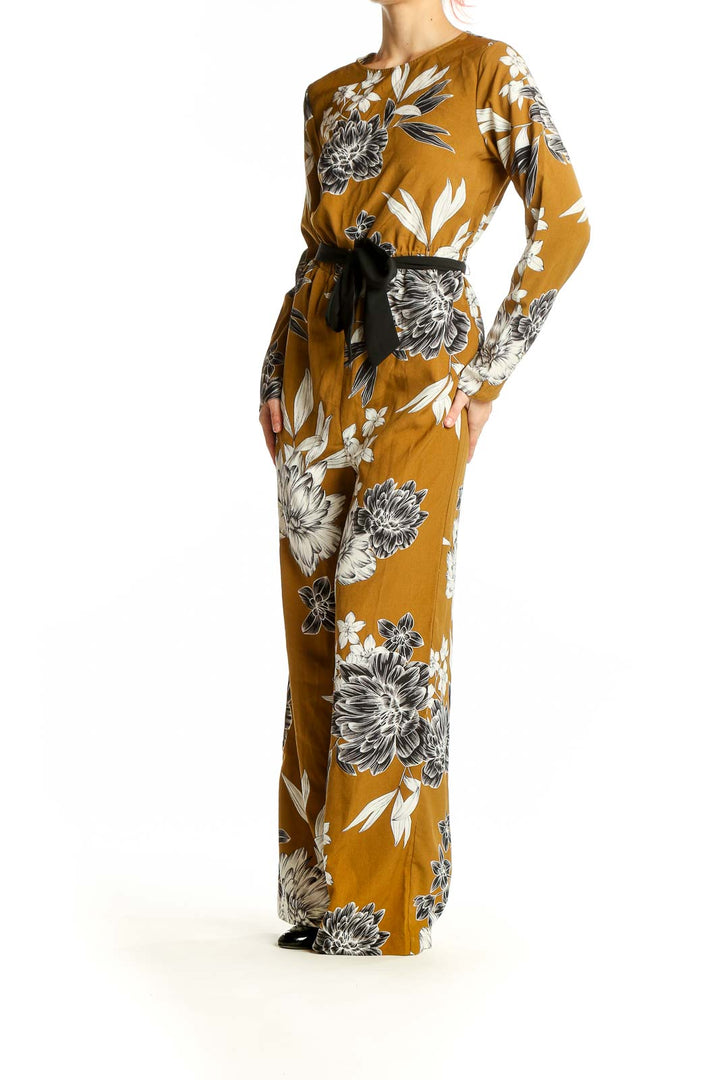 Front view of SilkRoll mustard floral long sleeve jumpsuit with black belt