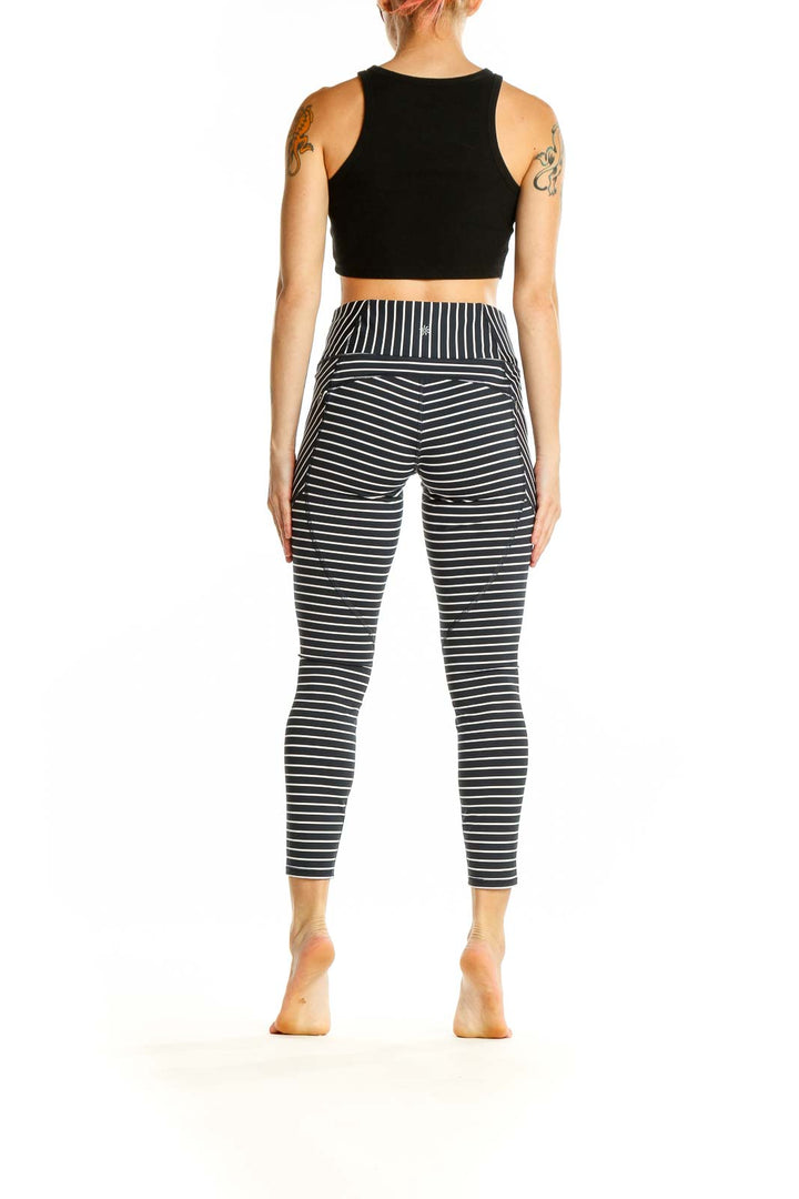 Side view of Athleta black and white striped athletic leggings on model with black crop top