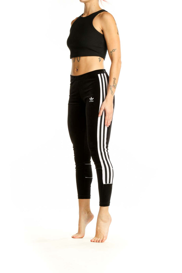 Front view of black velvet Adidas leggings with white side stripes