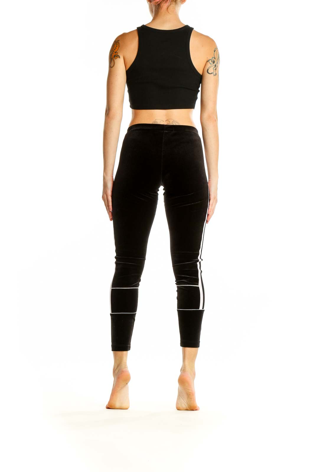 Side view of woman wearing black velvet Adidas leggings with white stripes