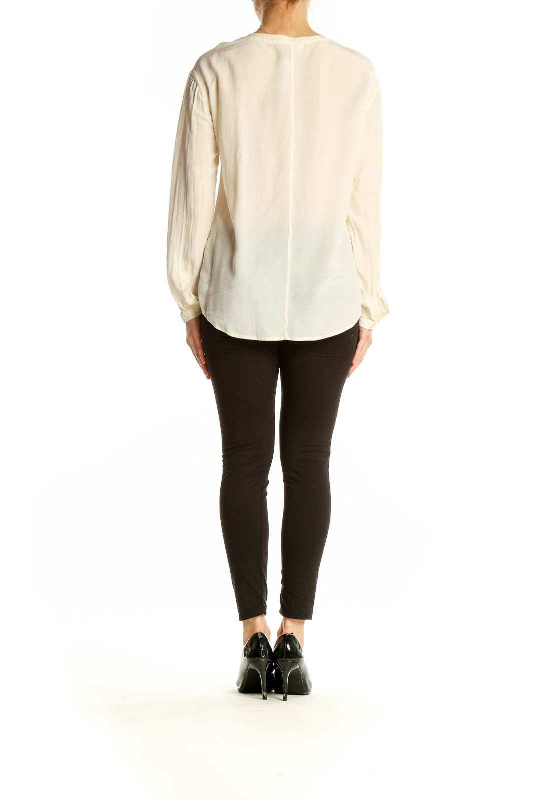 Side view of model wearing Everlane ivory silk blouse with black pants