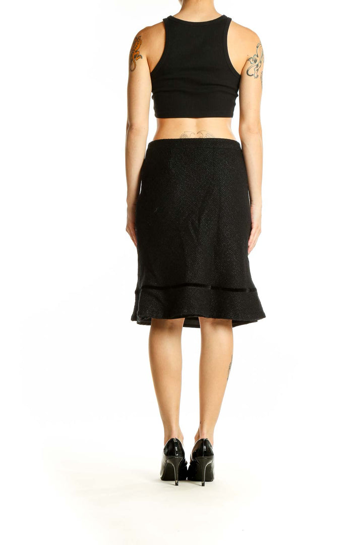 Side view of model wearing Athleta black wool blend flared skirt with black top