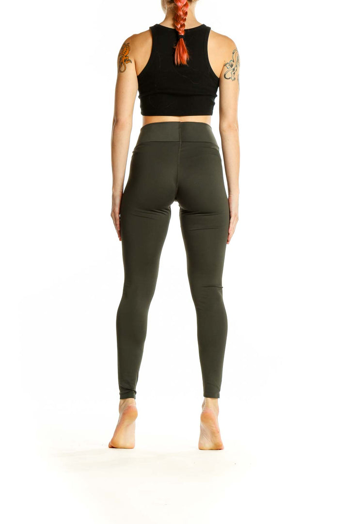 Side view of woman wearing olive Uniqlo high-waisted leggings with black crop top