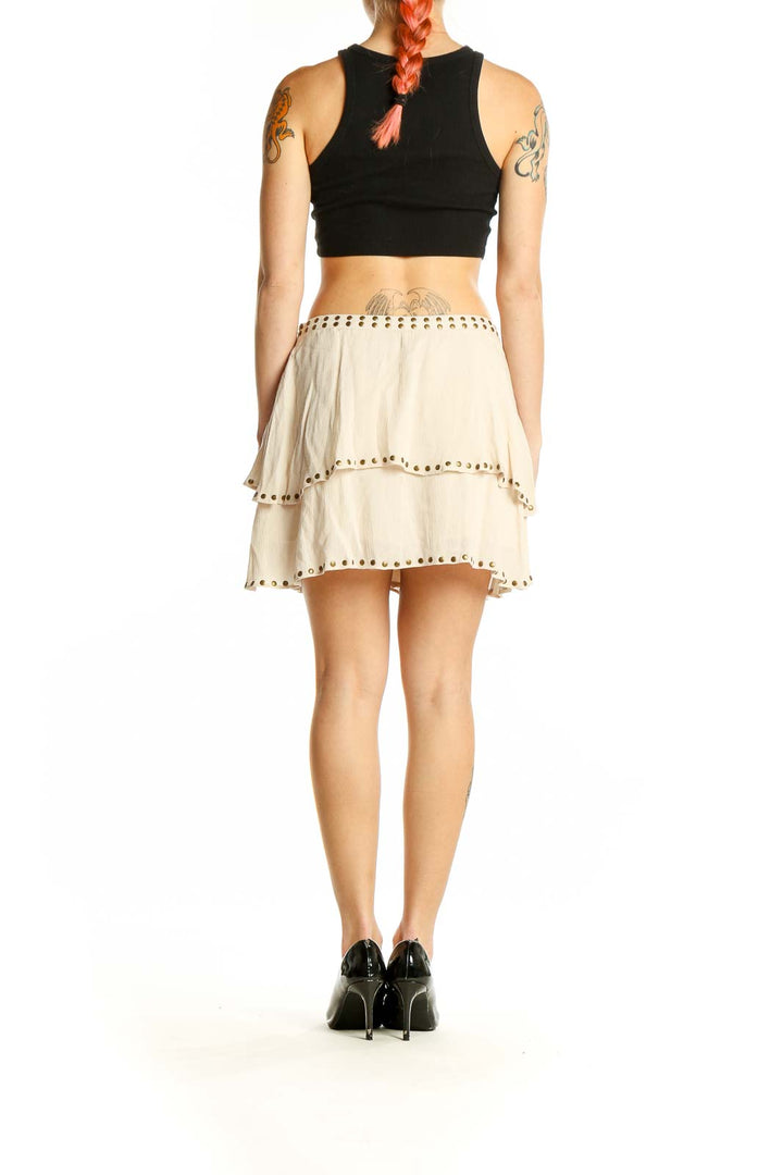 Side view of Ecote cream studded tiered mini skirt with black top