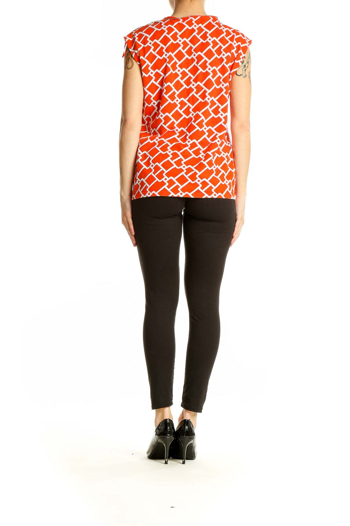 Back view of Michael Kors orange geometric print sleeveless top on model with black pants